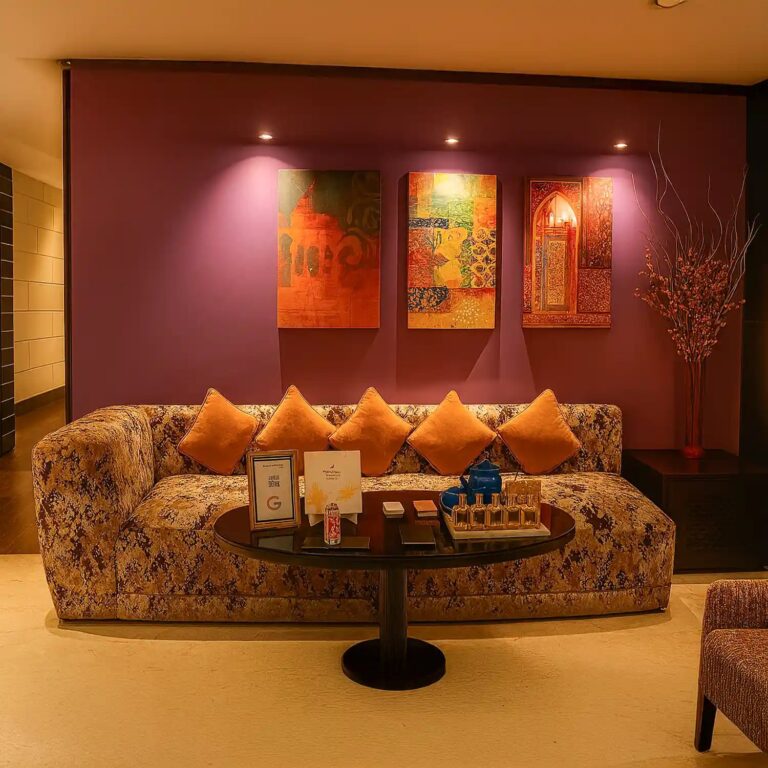Cozy lounge at Tattva Spa Grand Mercure Agra with patterned sofa, orange cushions, and vibrant wall art.