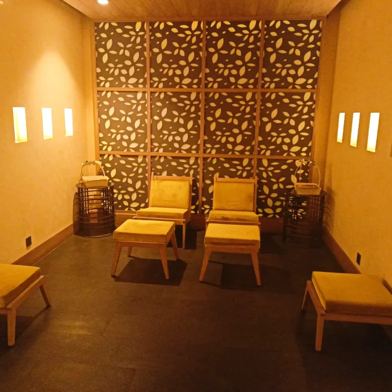 Warmly lit spa lounge at Tattva Spa in Radisson Udyog Vihar Gurgaon with wooden chairs and relaxing ambience.