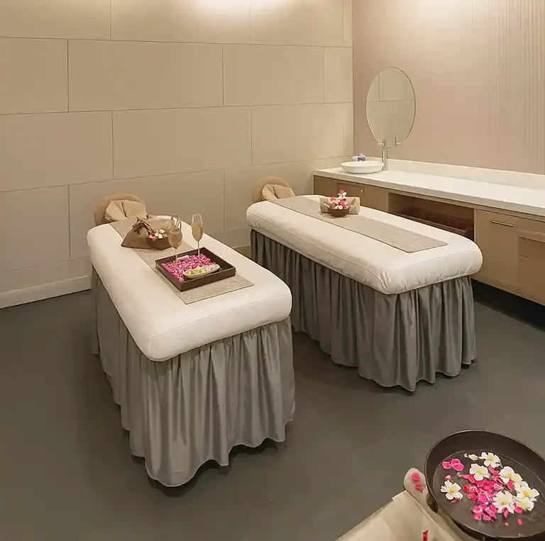 Elegant couple massage room with twin beds and flower arrangements at Tattva Spa Radisson Udyog Vihar Gurgaon.