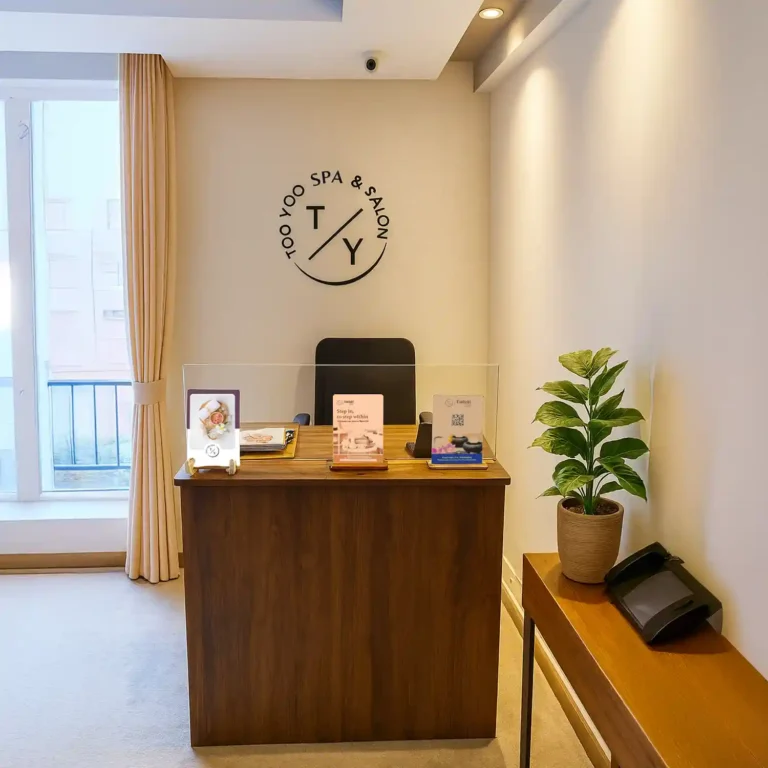 Reception desk at Too Yoo Spa & Salon by Tattva with clean wooden counter, plant décor, and natural light.