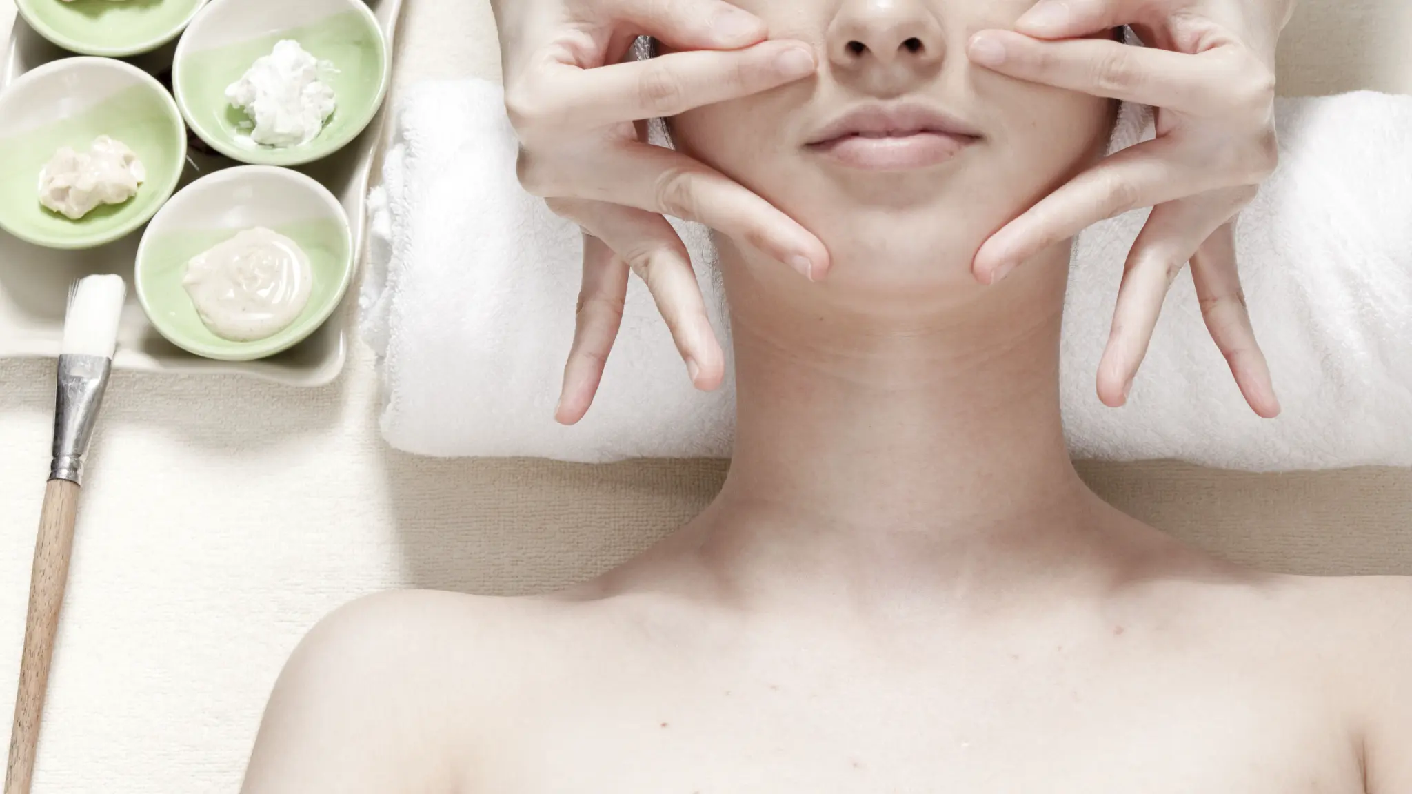 A woman lying on spa bed and getting face massage