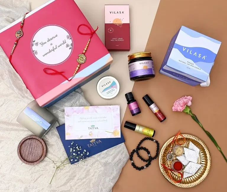 An elegant Last-Minute Rakhi Gifting setup with a pink gift box, Tattva Spa gift card, Vilasa wellness products, traditional rakhi, sweets, and roli chawal arranged aesthetically on a beige background, symbolizing festive love and thoughtful surprises.