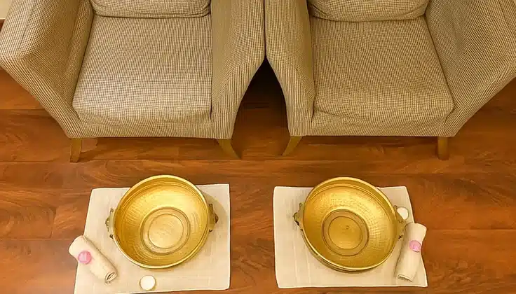 Foot ritual setup with brass bowls and towels in a spa treatment area.