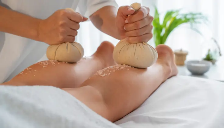 Warm herbal potli placed on the feet during a relaxing Potli massage, helping relieve deep muscle tension and improve circulation at the spa.