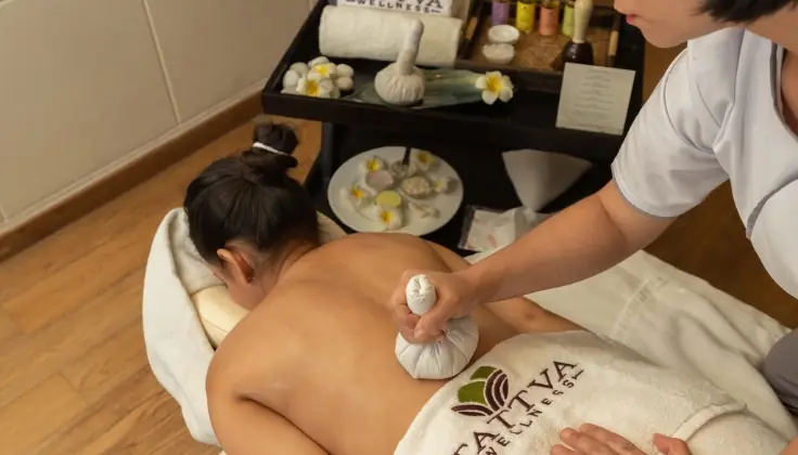 A woman receiving a Potli massage as warm herbal bundles are gently applied to relieve tension, boost immunity, and provide deep comfort and relaxation.