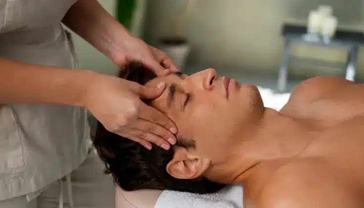 Male client receiving a relaxing Indian head massage from a professional therapist in a calm spa setting, focused on stress relief and wellness.