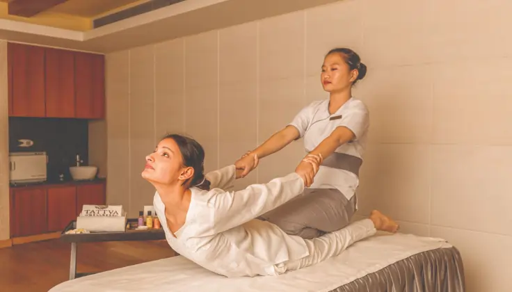 A therapist assisting a guest with Tattva Signature Yoga Massage in a serene spa setting.