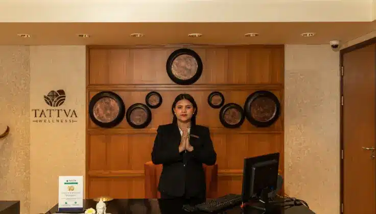 Tattva Wellness Spa manager greeting guests with a namaste at the reception desk.