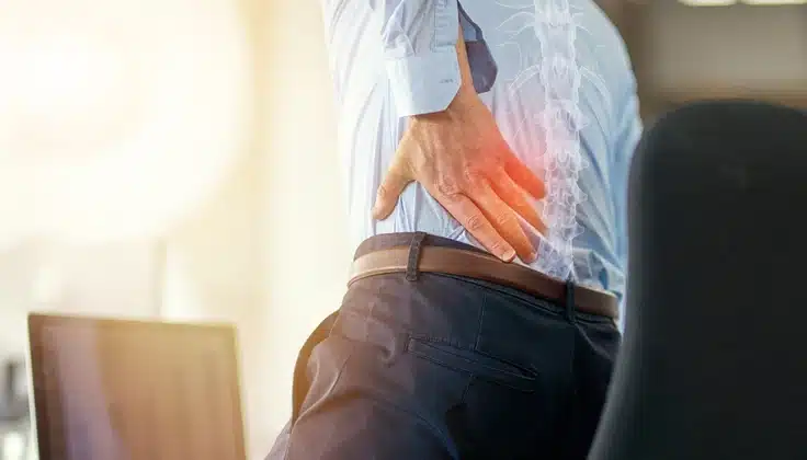 IT professional experiencing lower back pain from prolonged sitting, a common concern addressed through deep tissue massage.