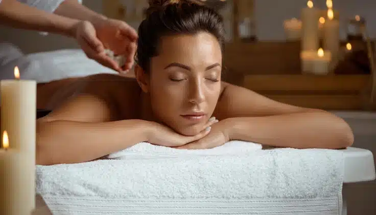 Woman relaxing during a soothing back massage in a candlelit spa setting.
