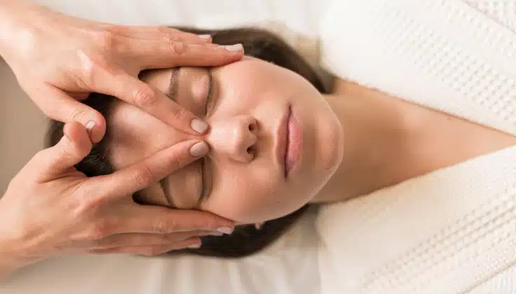 Woman receiving a gentle facial massage for relaxation and lymphatic support.