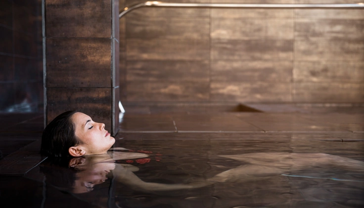 Woman relaxing in warm water during a hydrotherapy session for tired muscles.
