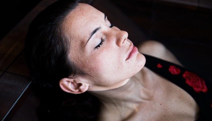 Woman relaxing in a warm Jacuzzi bath while experiencing hydrotherapy benefits for tired muscles.