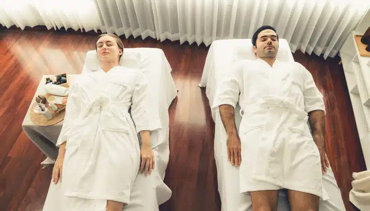 Couple relaxing side by side on separate spa beds before their massage session.
