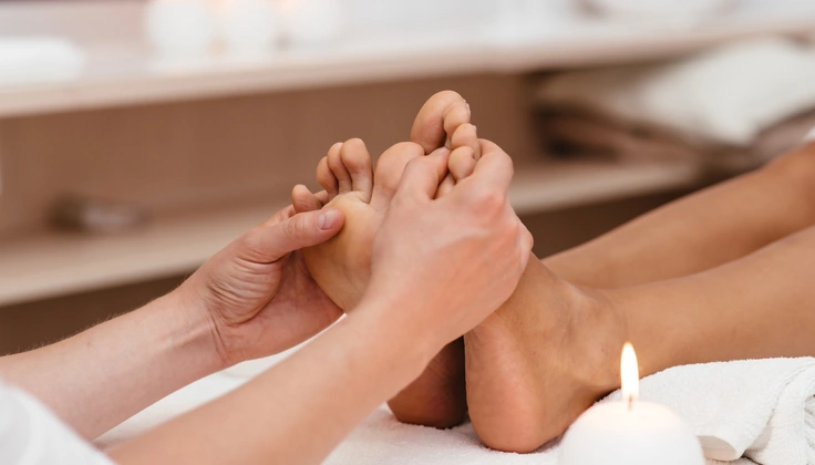 Therapist applying pressure to the soles of the feet during a reflexology massage.