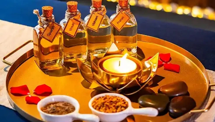 Spa massage oils, a lit diya, rose petals and wellness essentials arranged on a festive tray.
