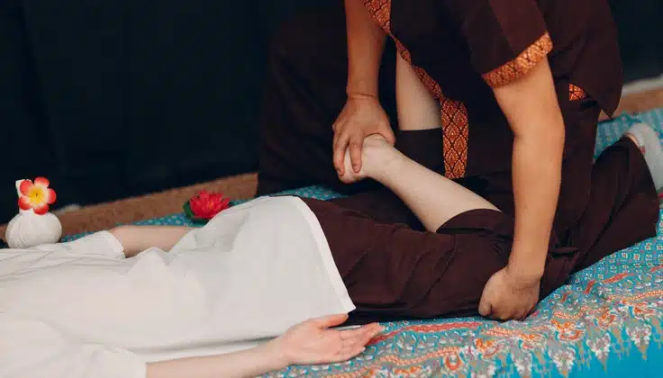 Therapist stretching a client's leg during a Thai massage session.