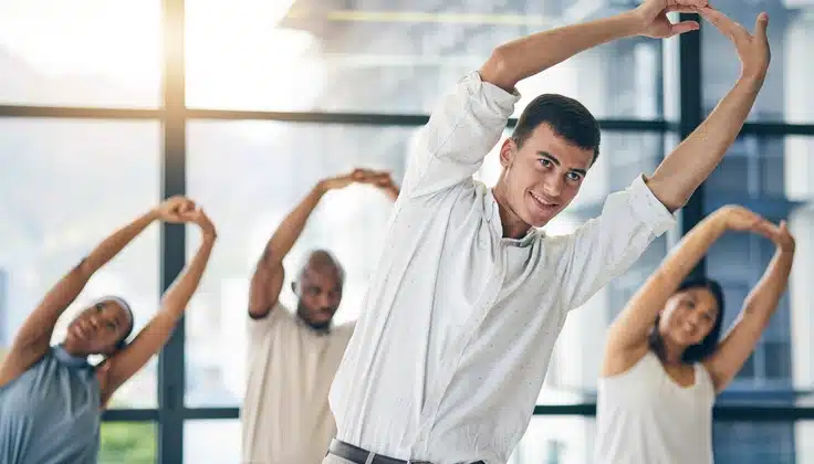 Corporate employees participating in a group stretching session as part of an employee wellness program.