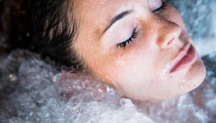 Woman relaxing with her eyes closed in a bubbling jacuzzi during a spa session.